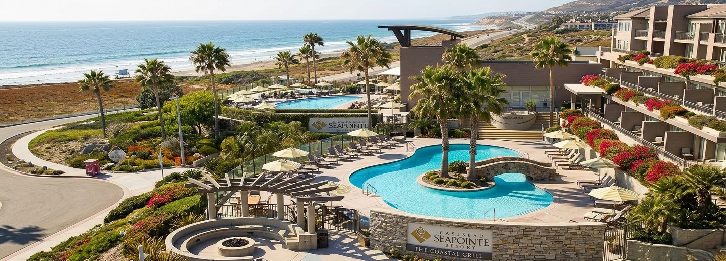Poolside resort with palm trees, curved pool, sun loungers, and ocean view&mdash;lively courtyard, hotel balconies, and beach beyond.